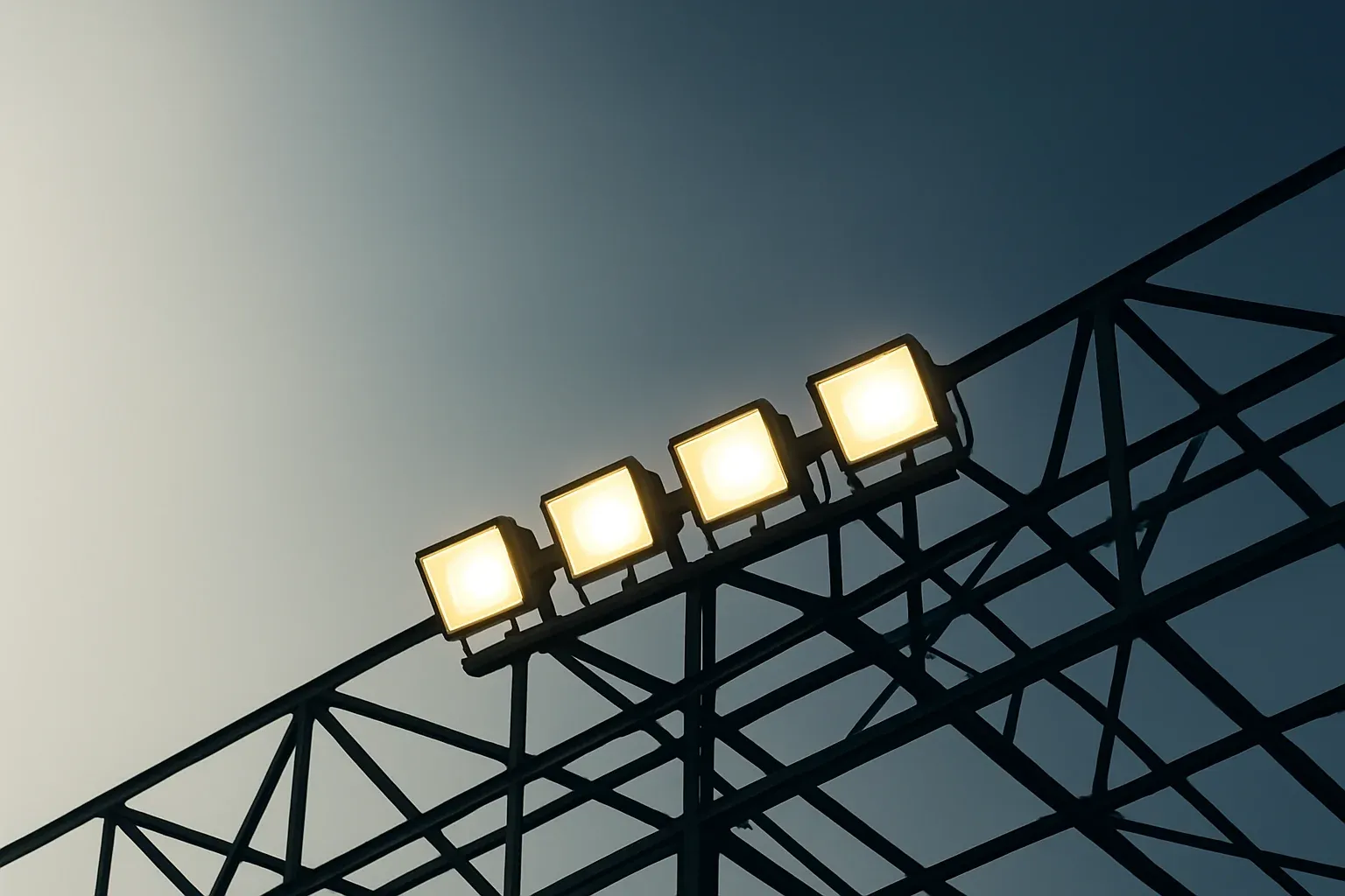 Looking up at bright stadium floodlights against darkening blue sky